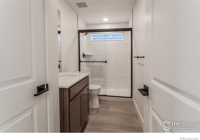 full bath featuring visible vents, a shower stall, toilet, wood finished floors, and vanity