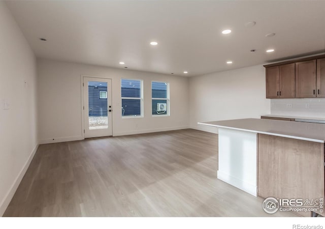 kitchen featuring backsplash, baseboards, light countertops, recessed lighting, and light wood-style flooring