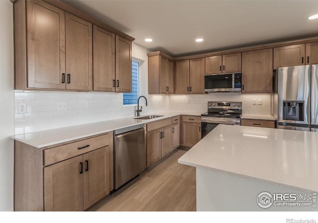 kitchen featuring decorative backsplash, light countertops, appliances with stainless steel finishes, and a sink