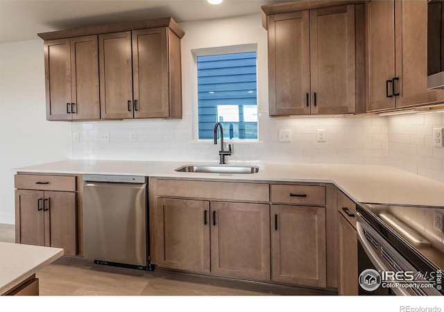 kitchen with dishwasher, light countertops, decorative backsplash, and a sink