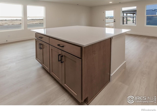 kitchen with baseboards, a kitchen island, light wood-style flooring, and light countertops