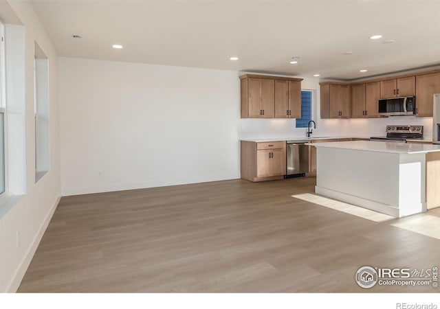 kitchen with recessed lighting, a sink, stainless steel appliances, light countertops, and light wood-style floors