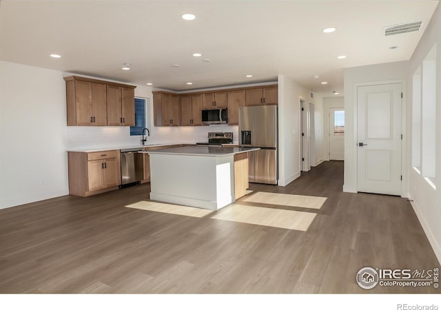 kitchen with visible vents, recessed lighting, wood finished floors, stainless steel appliances, and a sink