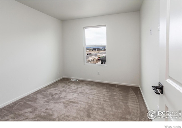 empty room featuring carpet flooring, baseboards, and visible vents