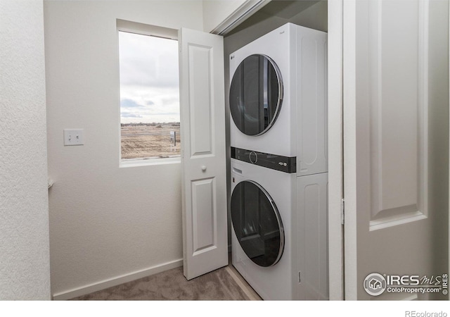 washroom featuring carpet flooring, baseboards, laundry area, and stacked washing maching and dryer