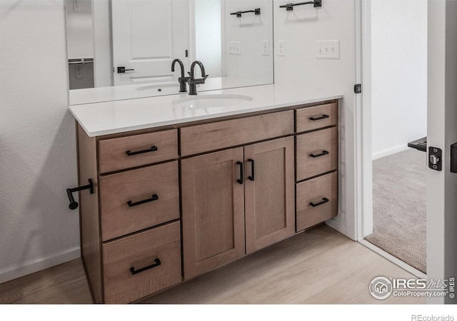 bathroom with vanity, wood finished floors, and baseboards