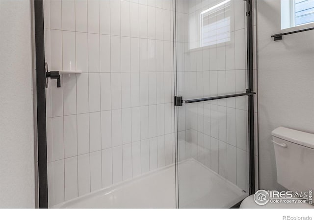 full bathroom featuring a stall shower and toilet