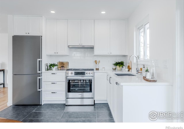 kitchen featuring a sink, under cabinet range hood, white cabinetry, stainless steel appliances, and light countertops