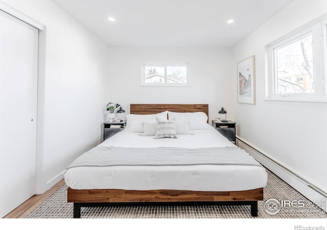 bedroom with recessed lighting, a baseboard radiator, and multiple windows