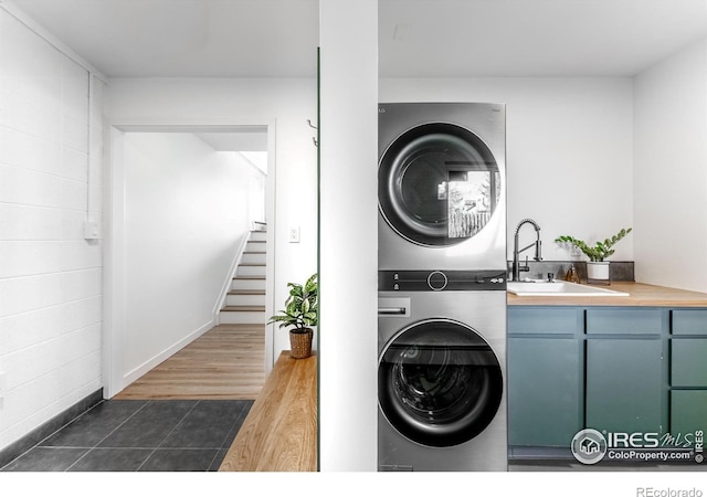 laundry room with a sink, dark wood-type flooring, and stacked washer and dryer