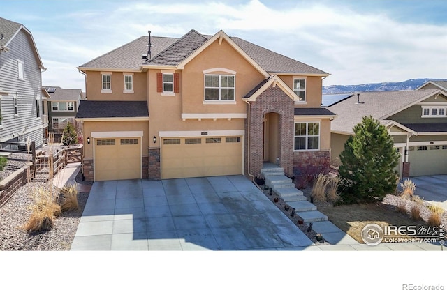 traditional home with roof with shingles, driveway, an attached garage, stucco siding, and stone siding