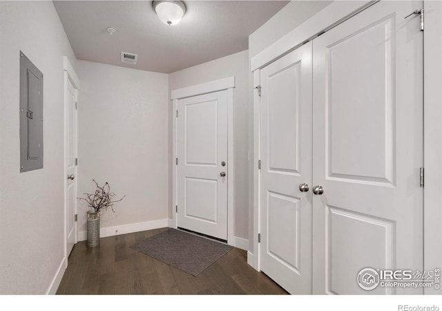 hall with electric panel, visible vents, baseboards, and dark wood-style floors