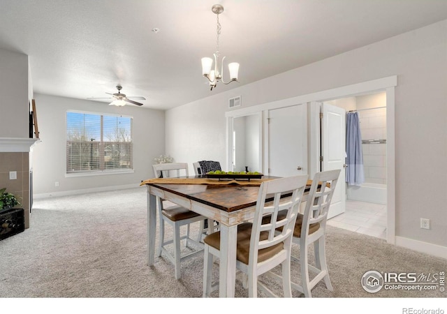 dining room featuring visible vents, baseboards, light colored carpet, and ceiling fan with notable chandelier