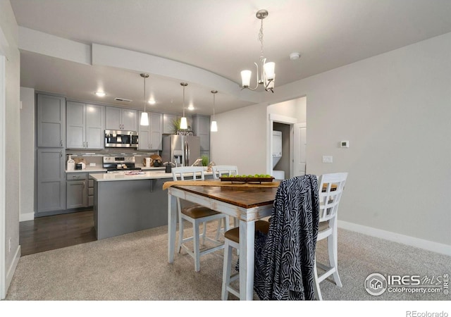 dining room with a chandelier, baseboards, and dark colored carpet