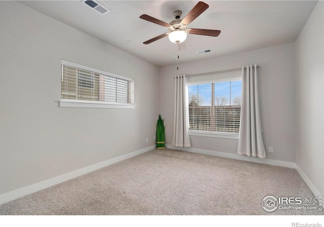 carpeted empty room featuring visible vents, a ceiling fan, and baseboards