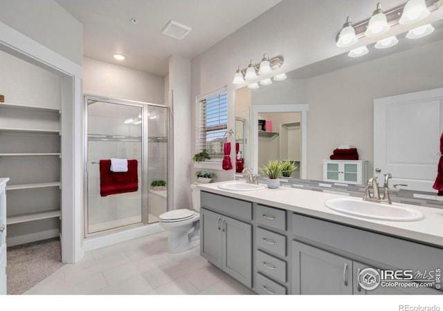 bathroom with double vanity, a stall shower, and a sink