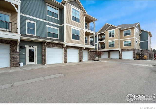 view of property featuring stone siding and a garage