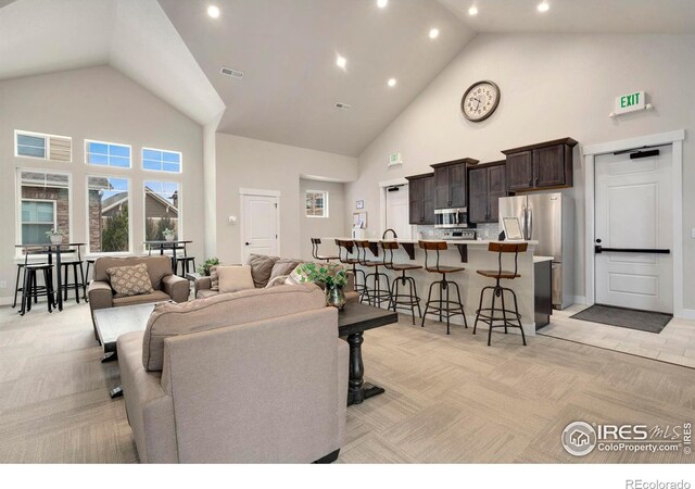 living room with recessed lighting, visible vents, light colored carpet, and high vaulted ceiling