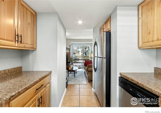 kitchen with light tile patterned floors, light brown cabinets, appliances with stainless steel finishes, and baseboards