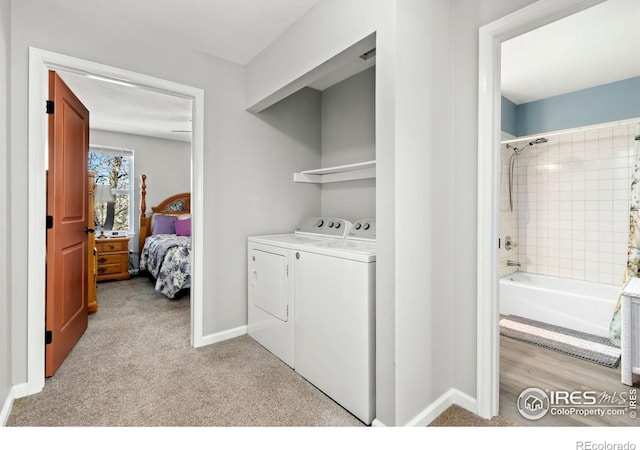 washroom featuring laundry area, washer and dryer, light colored carpet, and baseboards