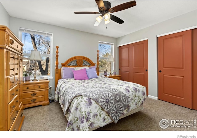 bedroom with light colored carpet, two closets, and a ceiling fan