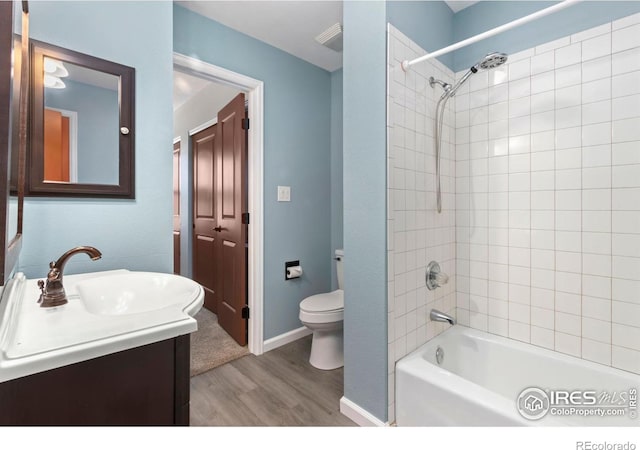 bathroom featuring vanity, wood finished floors, baseboards, bathtub / shower combination, and toilet