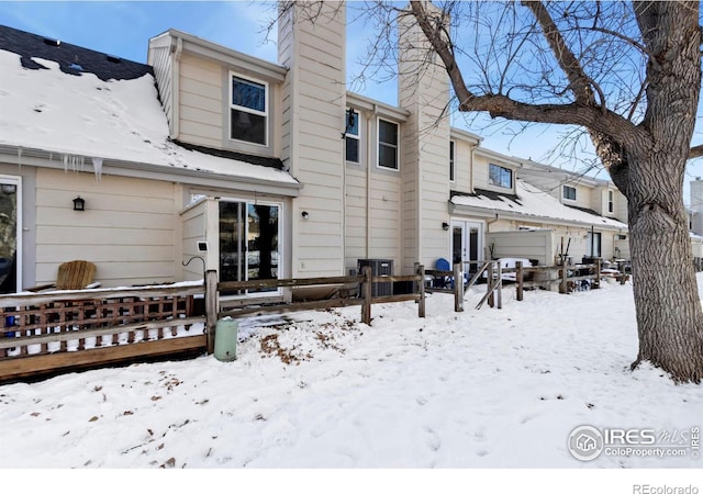 snow covered property with french doors, a chimney, and a garage