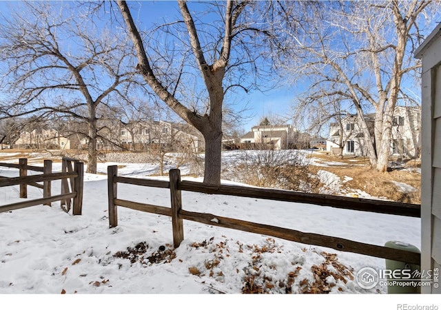 snowy yard featuring fence and a residential view