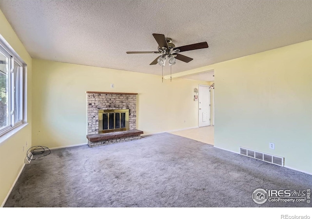 unfurnished living room with visible vents, a brick fireplace, a textured ceiling, and carpet floors