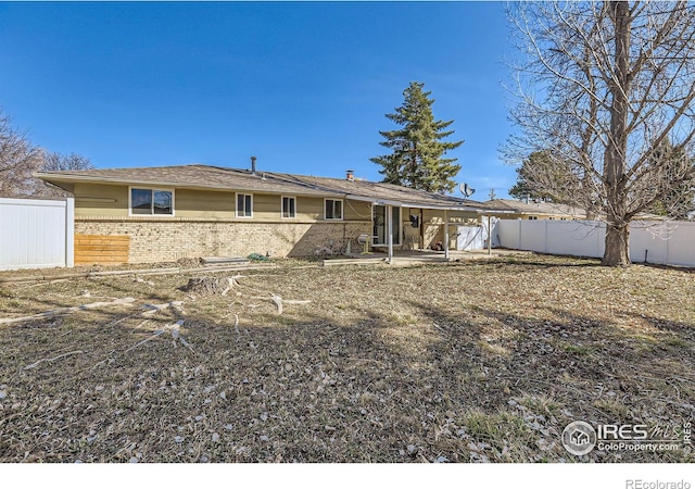 back of house with brick siding, a patio area, and a fenced backyard