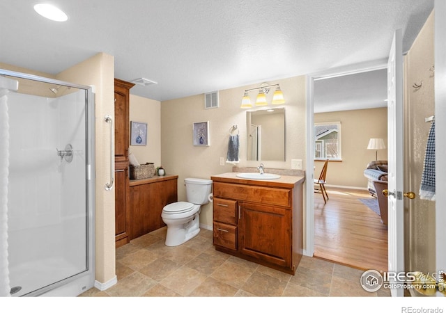 full bath featuring vanity, visible vents, a stall shower, a textured ceiling, and toilet