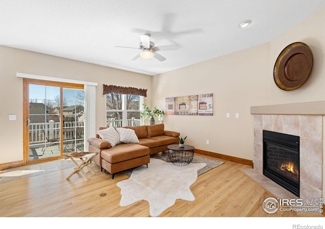 living room featuring a ceiling fan, wood finished floors, baseboards, and a tile fireplace