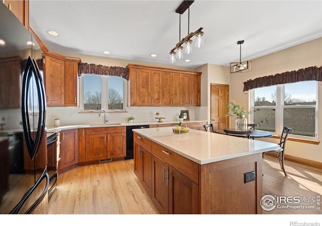 kitchen with a sink, brown cabinets, black appliances, and light countertops