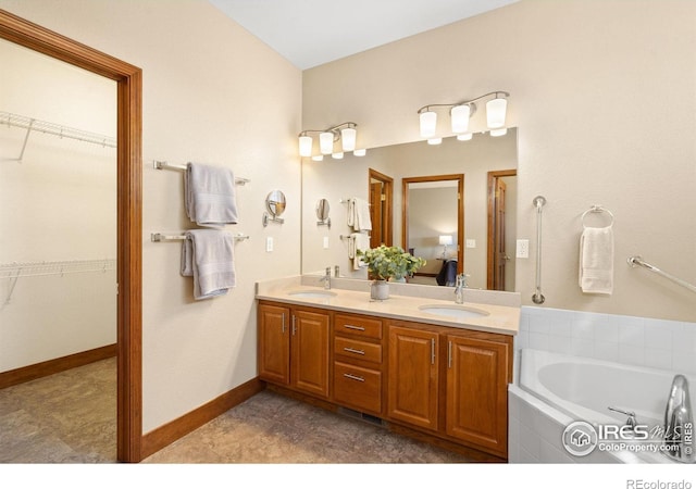 bathroom featuring double vanity, a bath, baseboards, and a sink