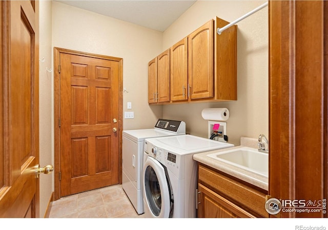 laundry room featuring light tile patterned floors, cabinet space, washing machine and dryer, and a sink