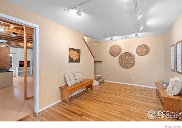 sitting room featuring stairway, rail lighting, baseboards, and light wood finished floors