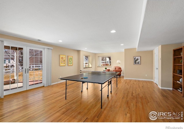 game room with a wealth of natural light, recessed lighting, light wood-style flooring, and french doors