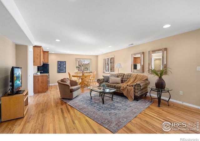 living area with recessed lighting, baseboards, and light wood finished floors