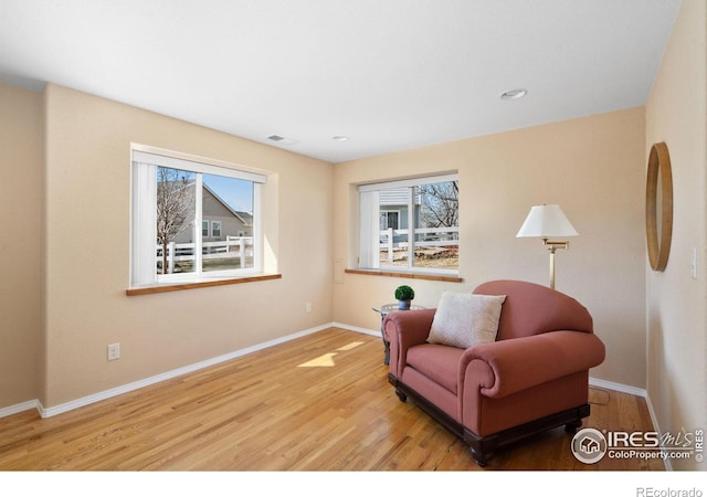 living area with recessed lighting, visible vents, baseboards, and wood finished floors