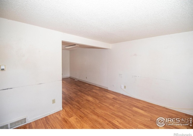 empty room featuring visible vents, a textured ceiling, and light wood-type flooring