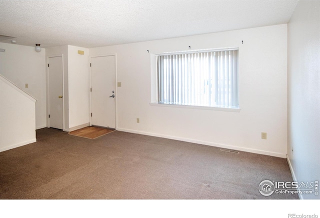 unfurnished room featuring visible vents, baseboards, a textured ceiling, and carpet