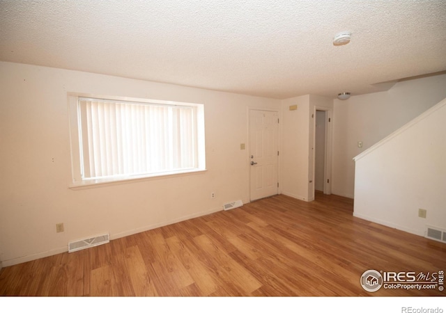 spare room with wood finished floors, visible vents, and a textured ceiling