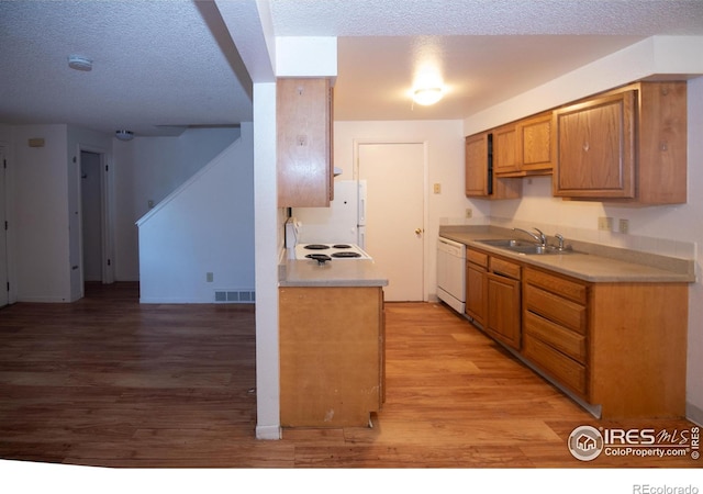 kitchen featuring visible vents, dishwasher, light countertops, light wood-style flooring, and a sink