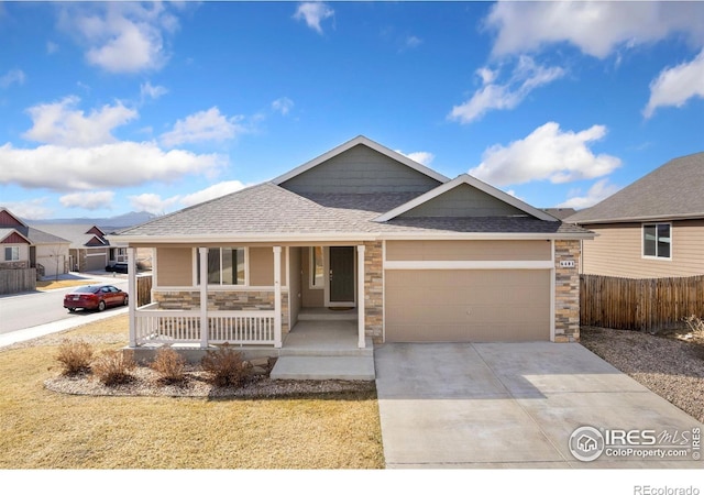 ranch-style home with stone siding, fence, covered porch, concrete driveway, and an attached garage