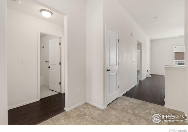 corridor with wood finished floors and baseboards