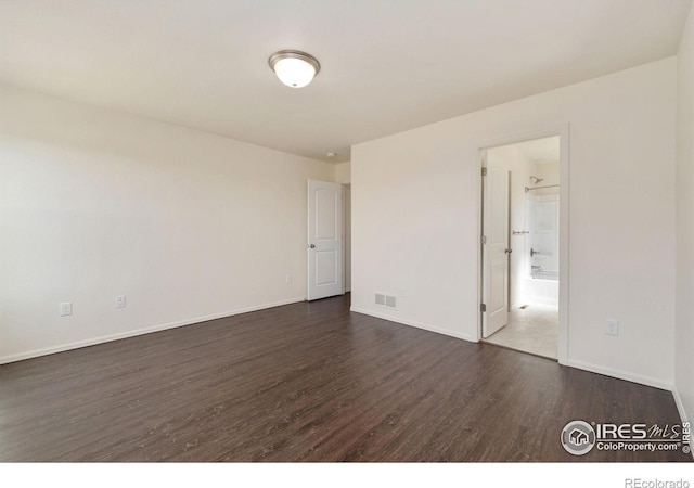 unfurnished room with dark wood-type flooring, baseboards, and visible vents