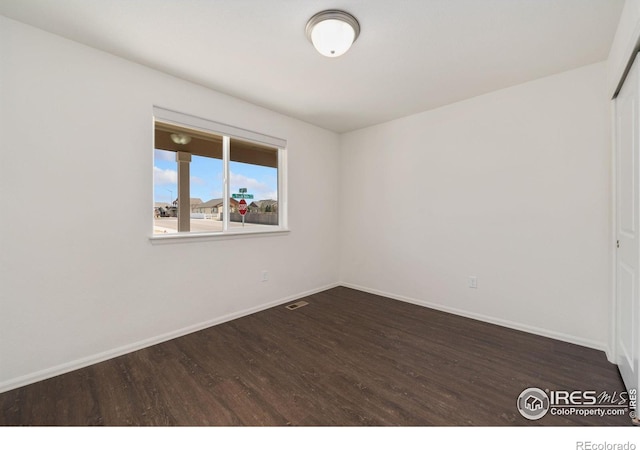 spare room with wood finished floors, visible vents, and baseboards