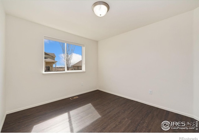 unfurnished room with visible vents, baseboards, and dark wood-type flooring