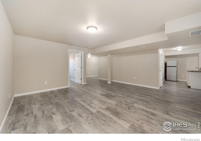 spare room featuring light wood-style floors, visible vents, and baseboards