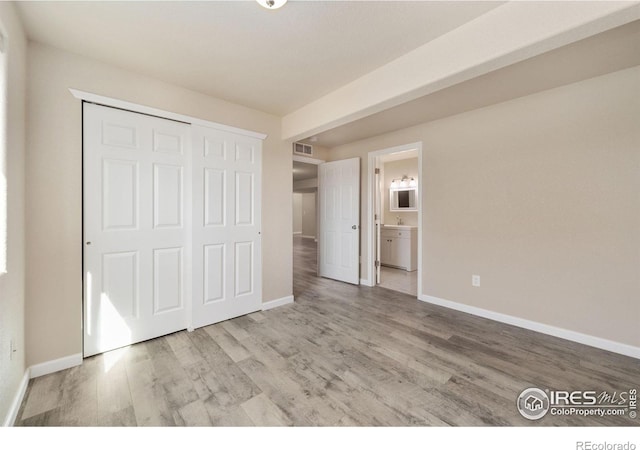 unfurnished bedroom with a closet, baseboards, and wood finished floors